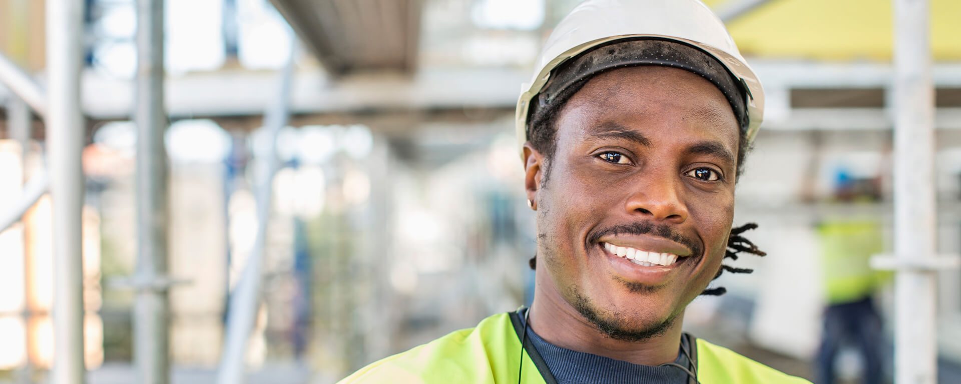 Worker wearing hard hat and high-viz jacket smiling.