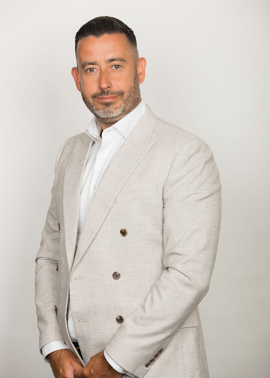 An image of David Purse standing in a cream suit and smiling at the camera.