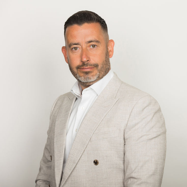 An image of David Purse wearing a white shirt and cream jacket. He is smiling at the camera.