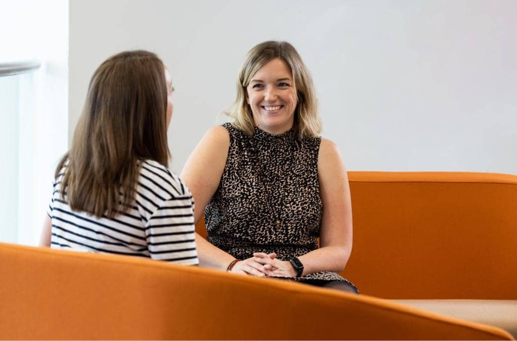 Two people laughing on a sofa