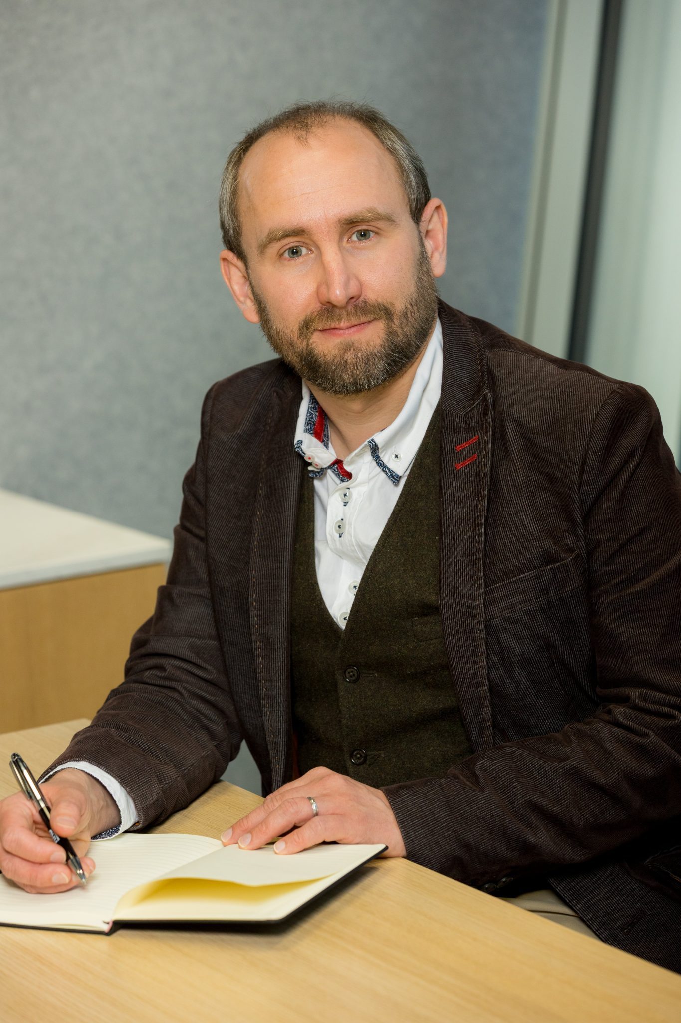 An image of Matthew Millyard sitting at a desk and writing in his notebook.