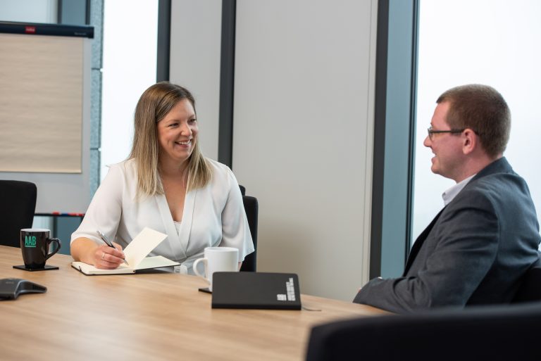 Members of the AAB Business Advisory team having a meeting and smiling.