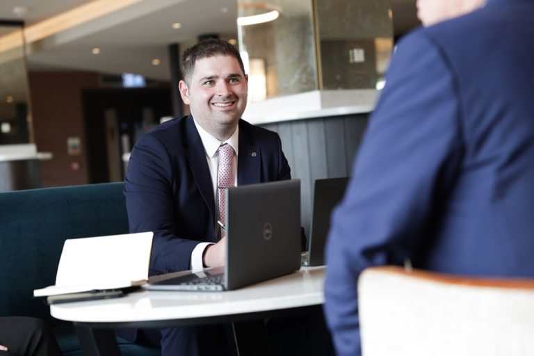 An AAB employee having a meeting and smiling at another person.
