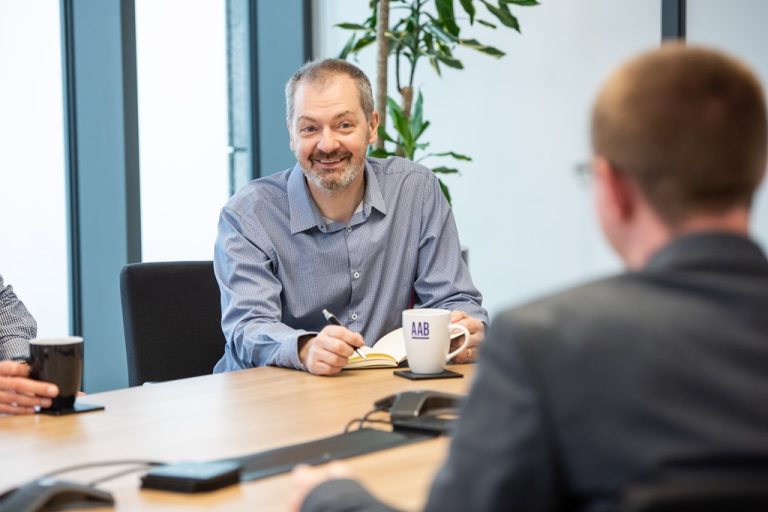 AAB employees sitting at a desk in a meeting.