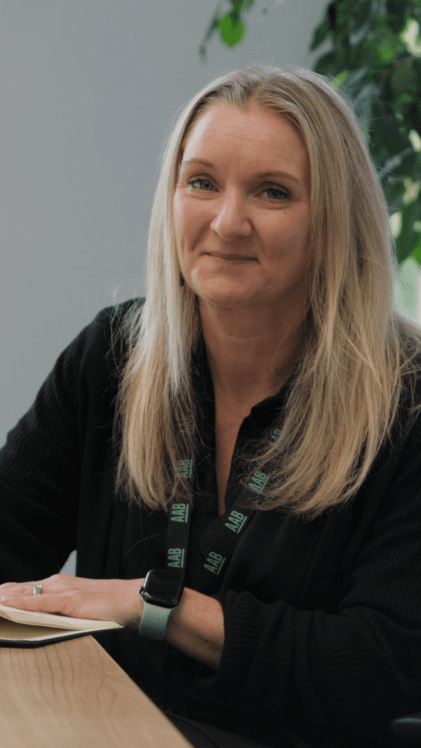 An image of Vicky Madigan wearing a black cardigan and writing at her desk.