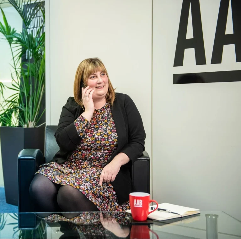 AAB team member sitting on a black chair and answering the phone.