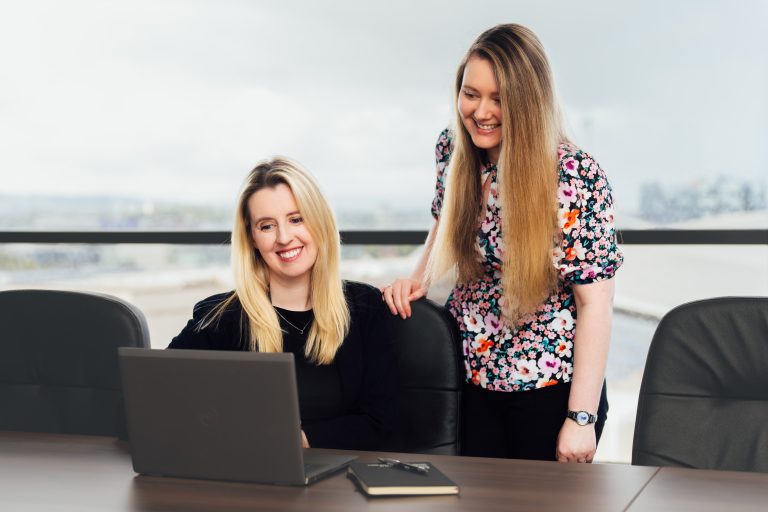 An image of two AAB employees working on a laptop.
