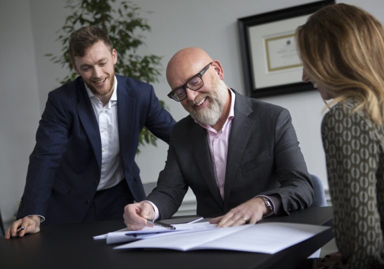 An image of a group of AAB employees sitting at a desk and chatting.