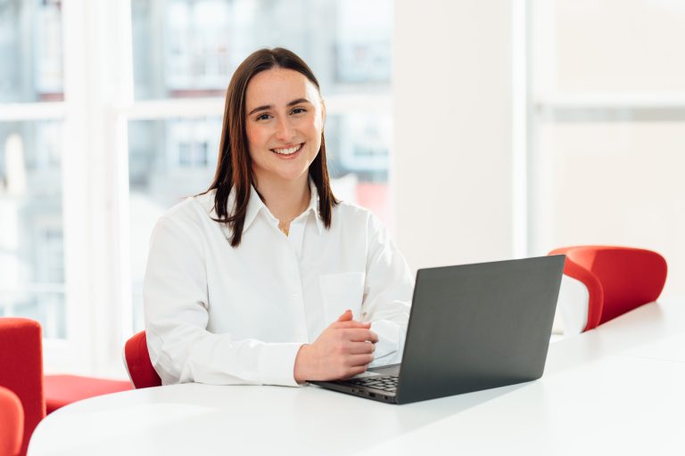 An image of Rebecca Morrison smiling at the camera with her laptop.