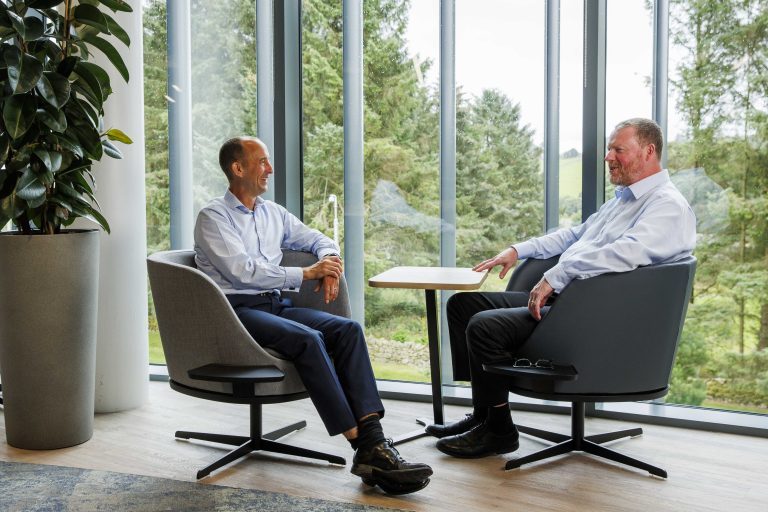 An image of two AAB employees working at a coffee table and chatting.