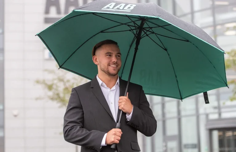 AAB Team member with umbrella and wearing a white shite and black blazer.