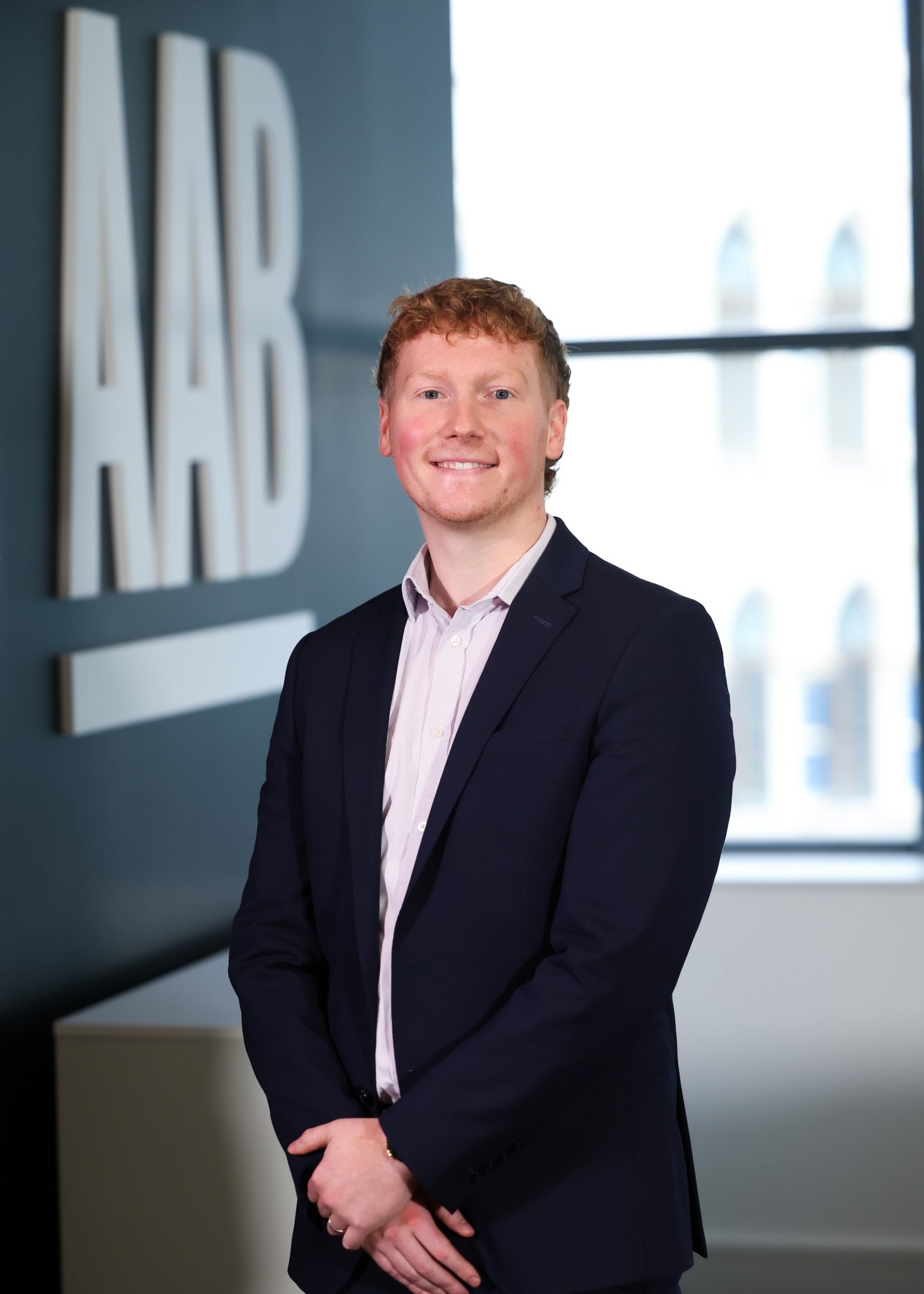 An image of Alexander Hill standing in the office with his hands clasped together.