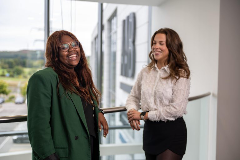 An image of two AAB employees on the AAB office balcony laughing together.