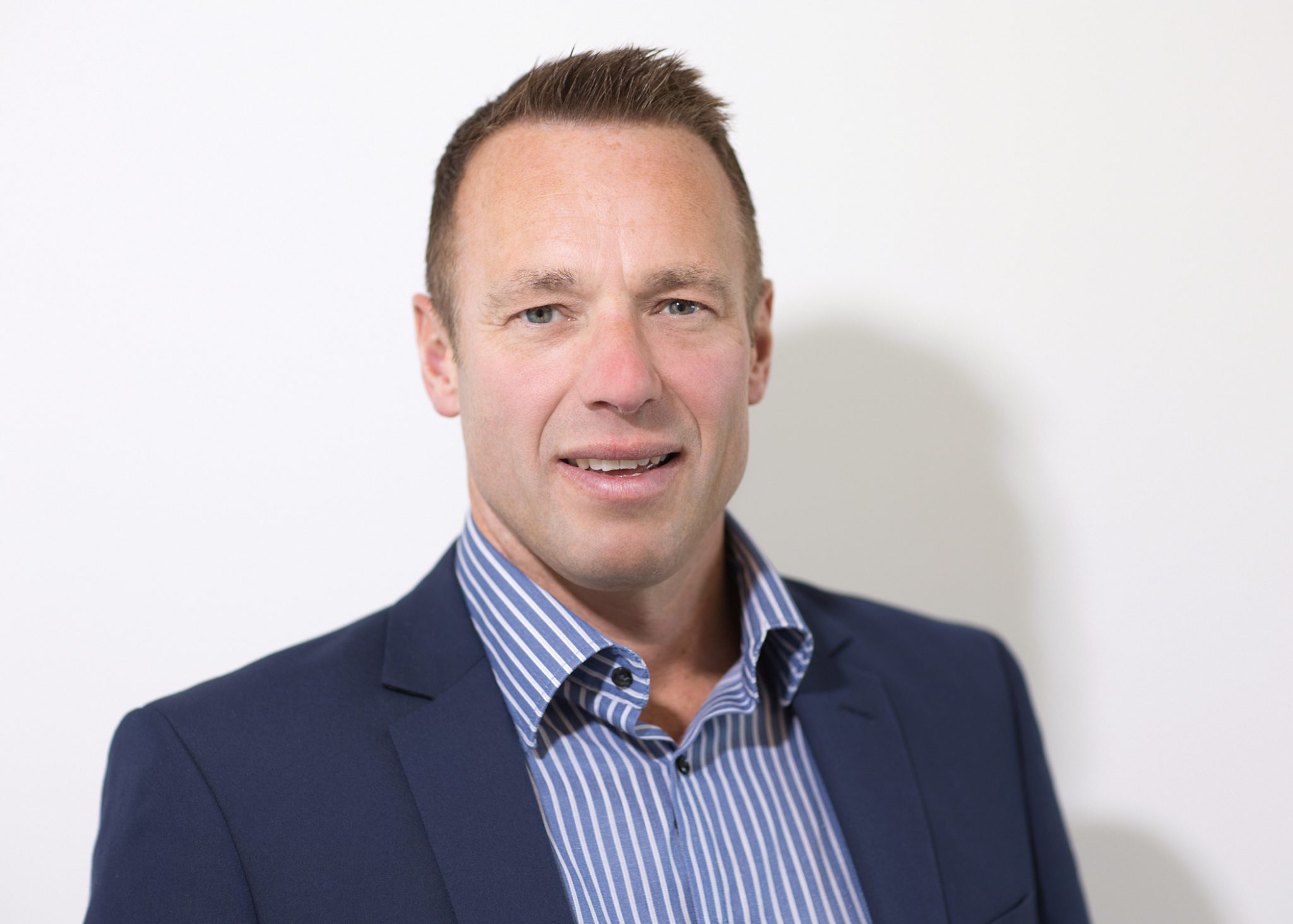An image of Gordon Steele wearing a shirt and blazer, whilst smiling at the camera.