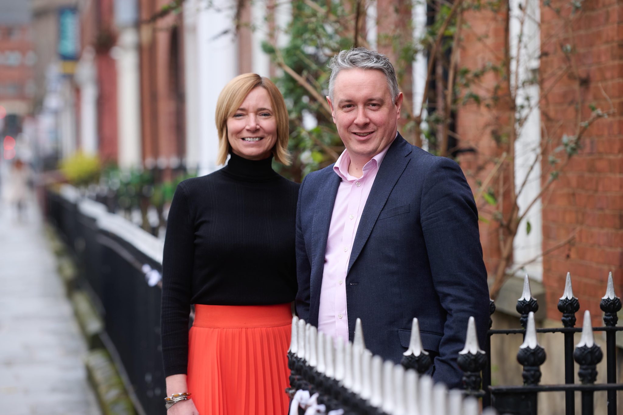 An image of Sarah Hex and James Hunt standing outside the Leeds office and smiling together for a press photoshoot.
