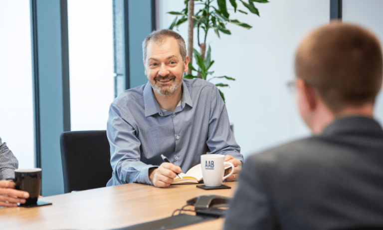 Alistair Duncan, in a meeting in the office smiling.