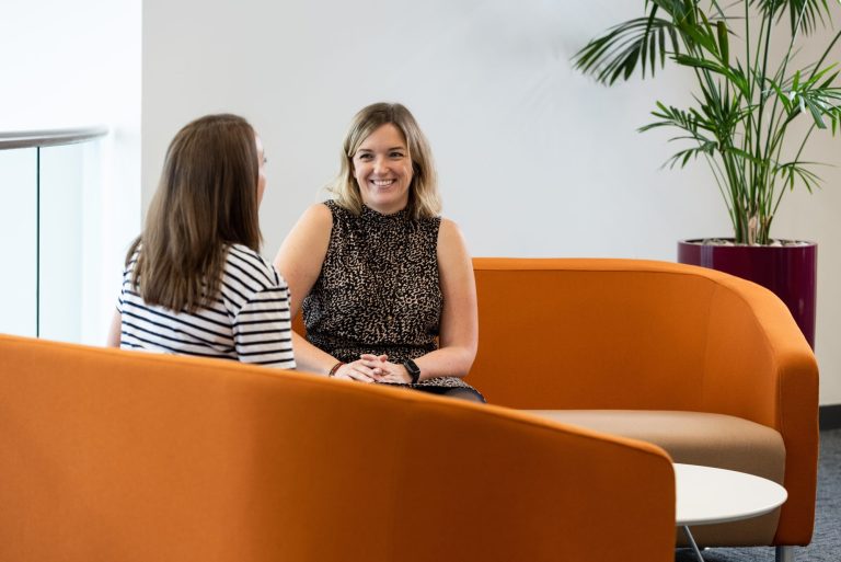 Two woman smiling in an office meeting at AAB.