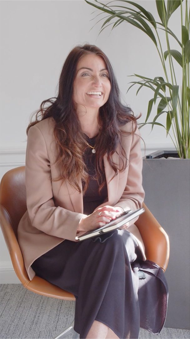 Helen Learmonth sitting on a office chair and writing in her notebook.