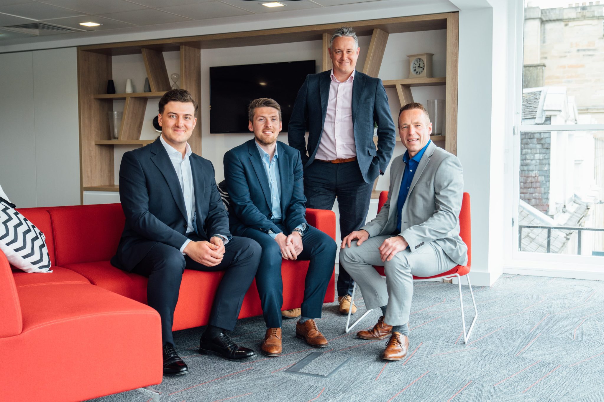 An image of four AAB team members sitting in the Edinburgh office and all wearing suits.