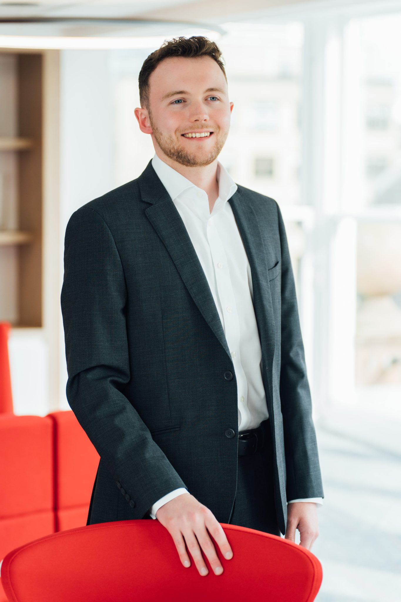 An image of Ben West standing in the Edinburgh office wearing a suit and smiling.