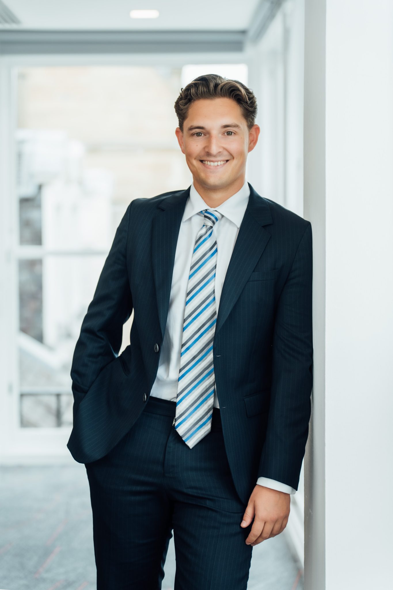An image of Jack Martin wearing a suit whilst leaning against the wall.