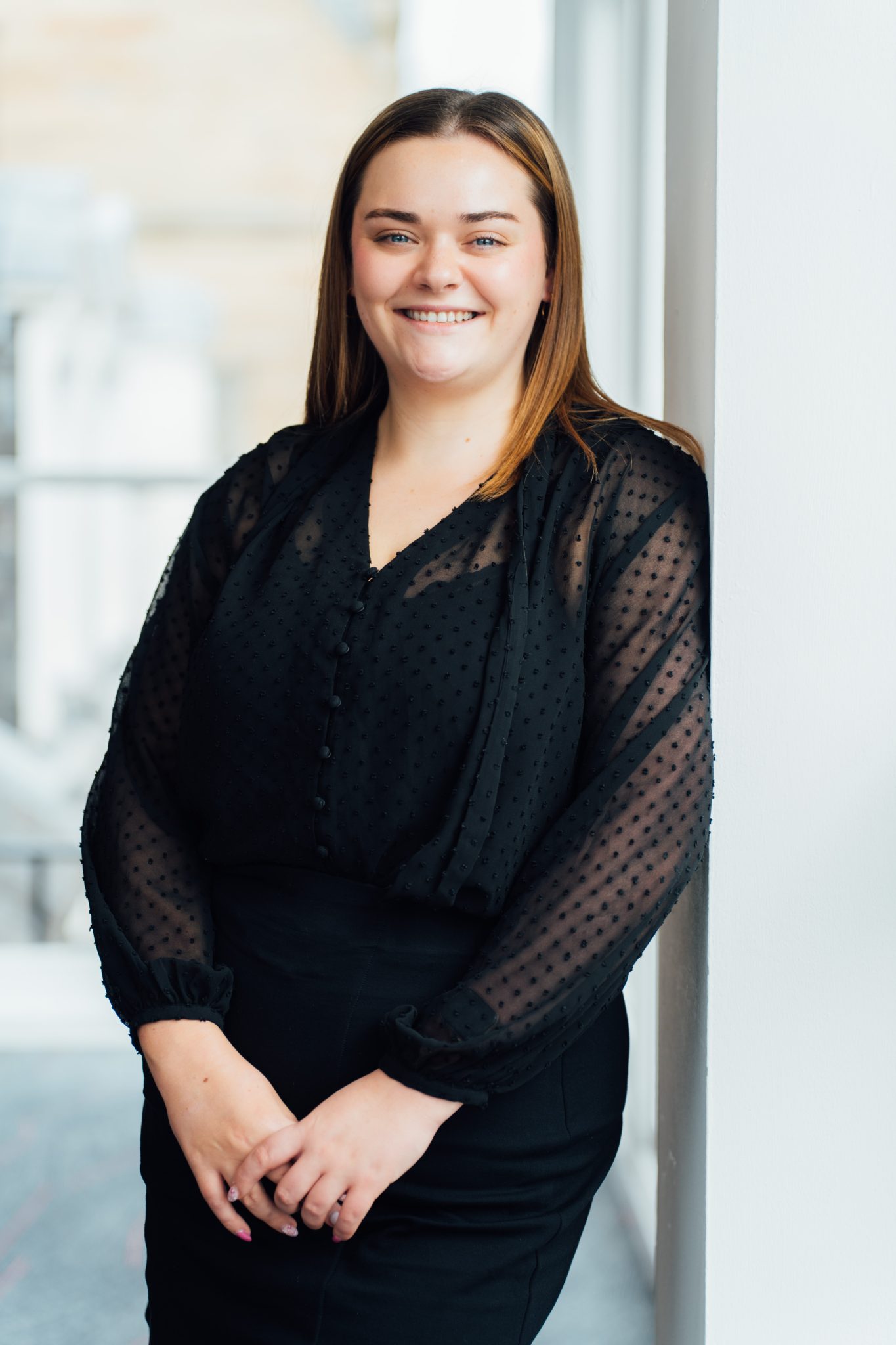 An image of Amy McLaughlin wearing a black outfit and smiling at the camera.