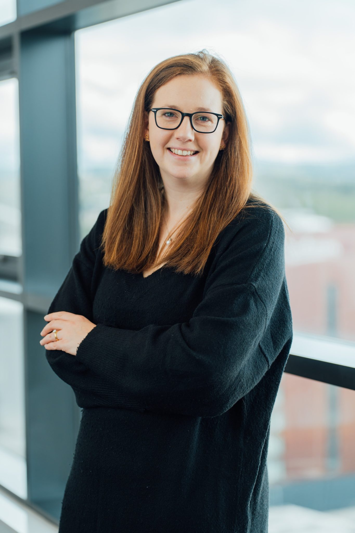 An image of Catherine Teenan with her hands crossed and leaning against a window.