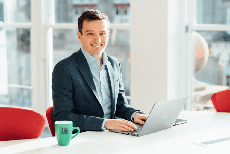 AAB employee smiling while working on laptop.