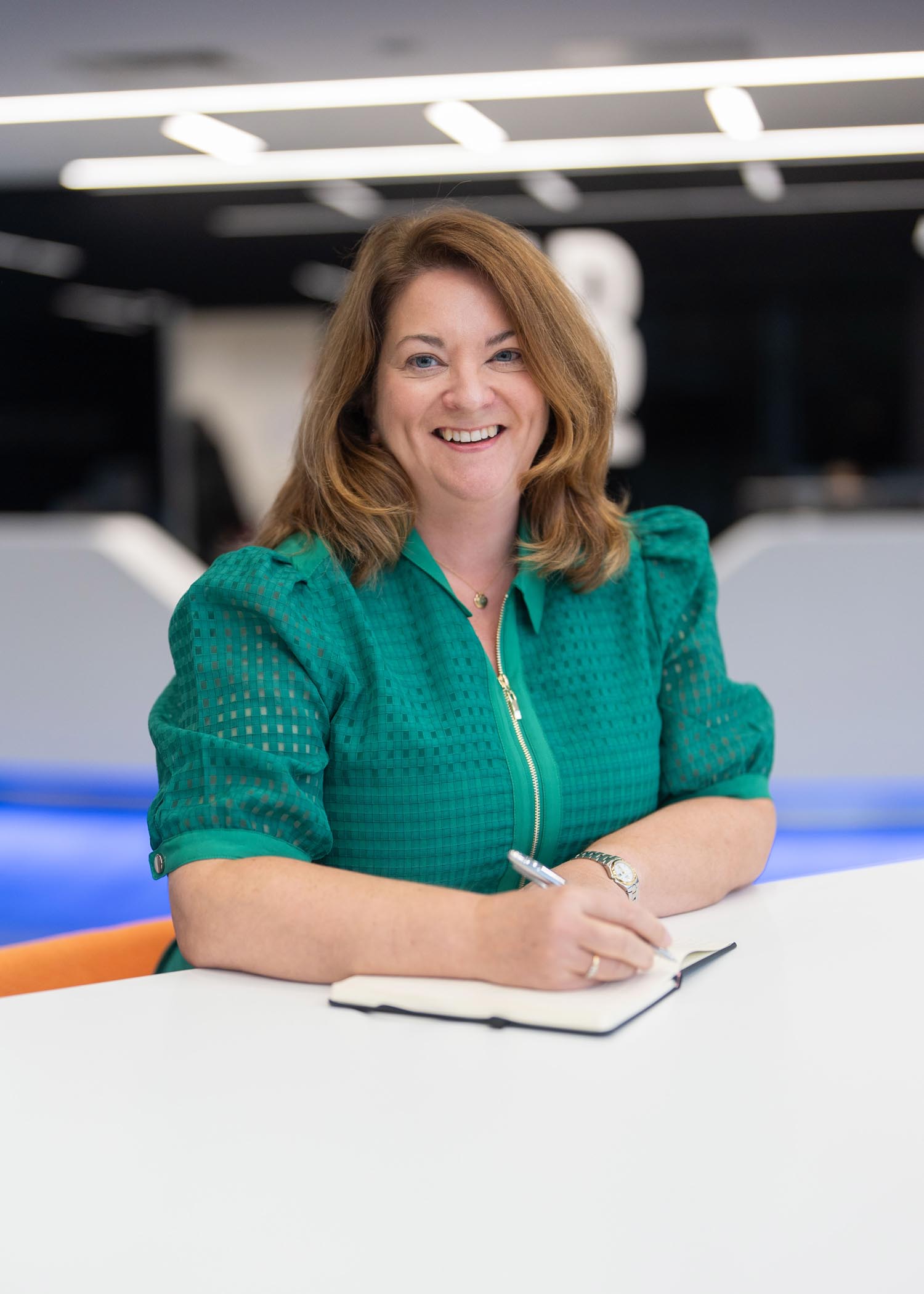 An image of Karen Lund standing at a desk and writing in her notebook.