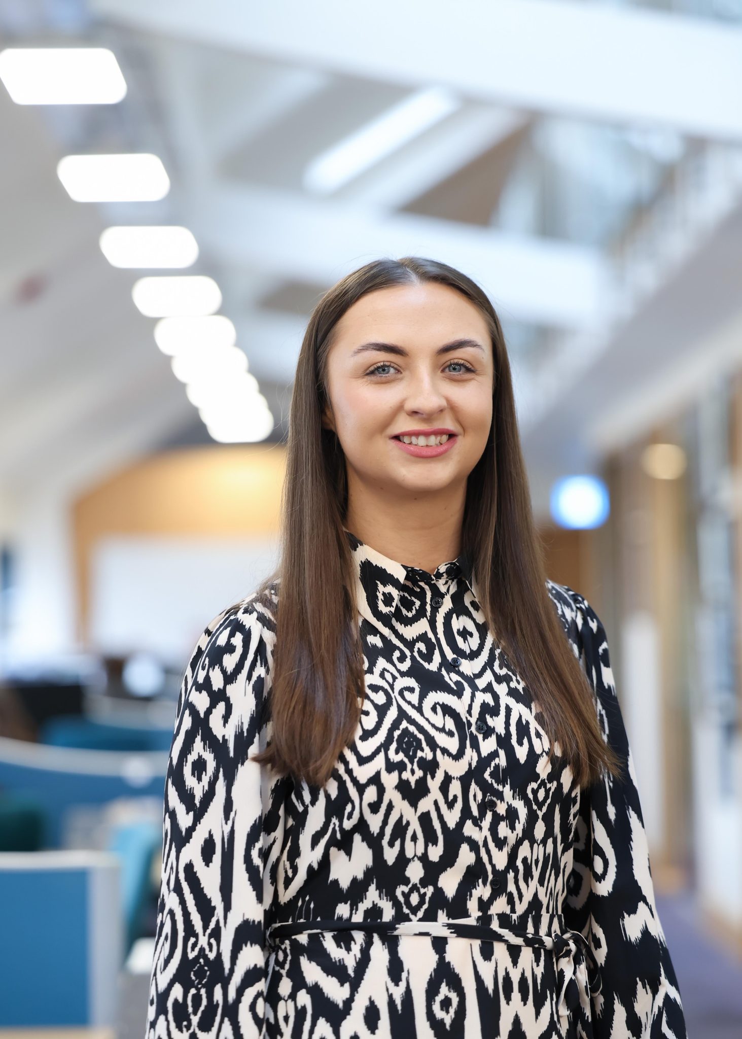 An image of Nisha Teeling standing in the office wearing a black and white top.