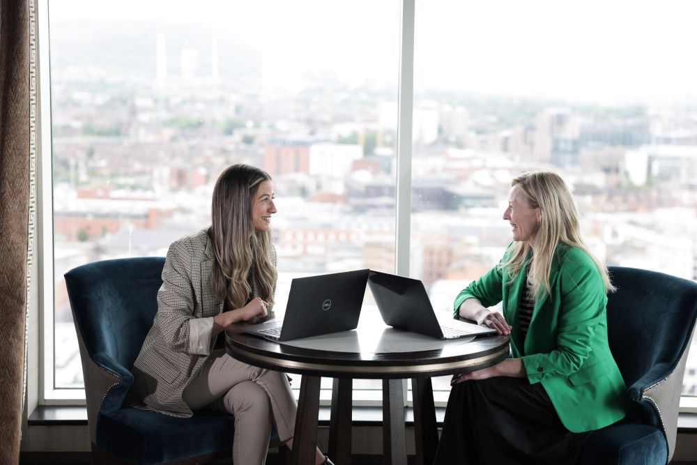Team members sitting in a meeting by the window on their laptops