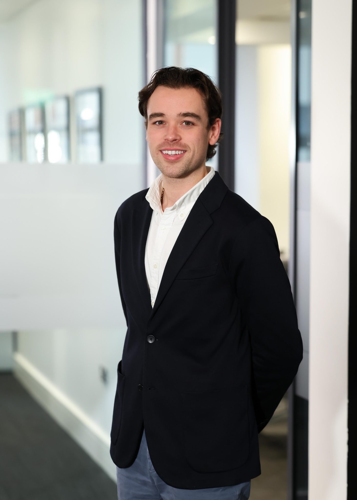 An image of Rory MacAllister standing in the Belfast office wearing a black blazer and white shirt.