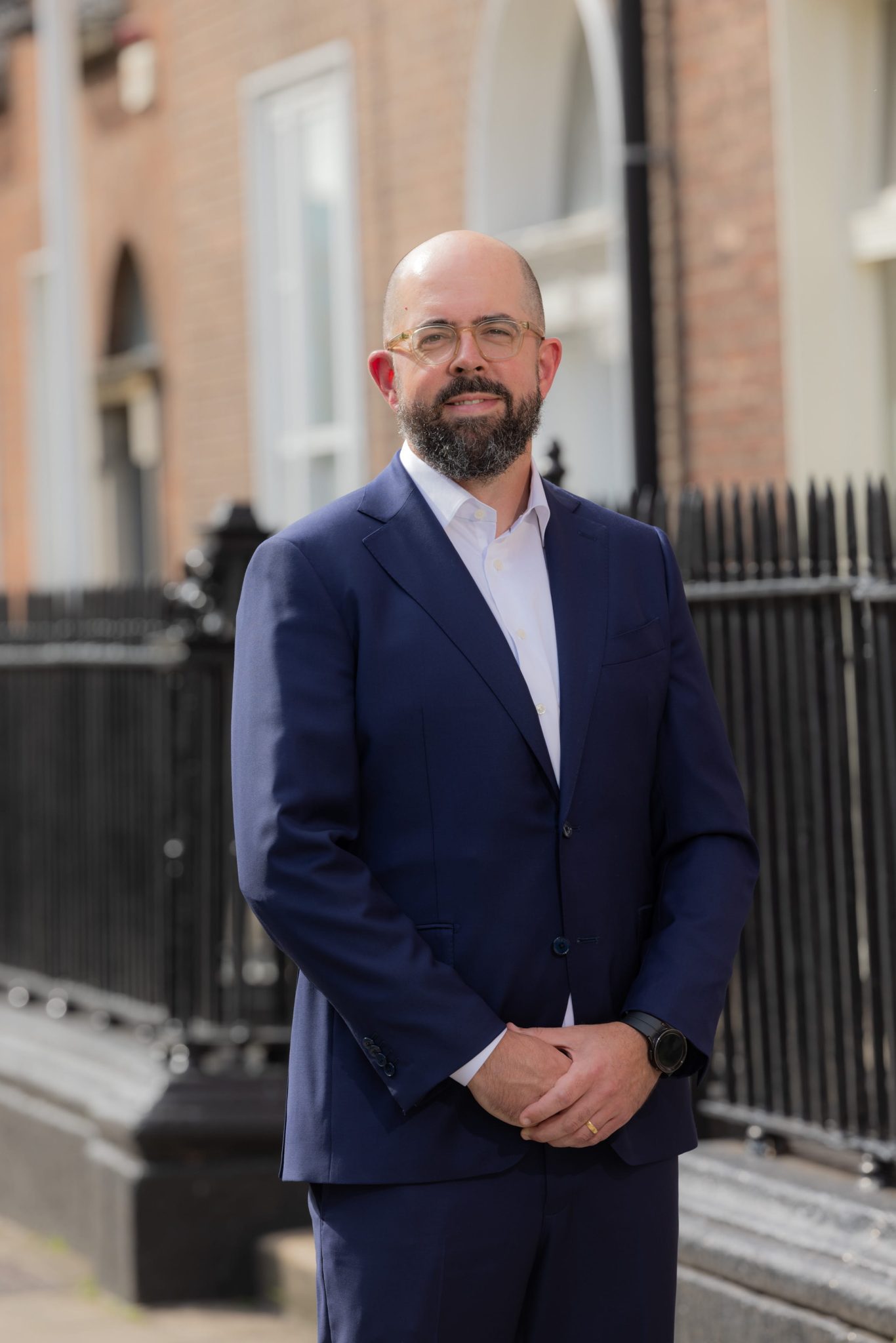 An image of Conor Ryan standing outside with his hands together and smiling at the camera.