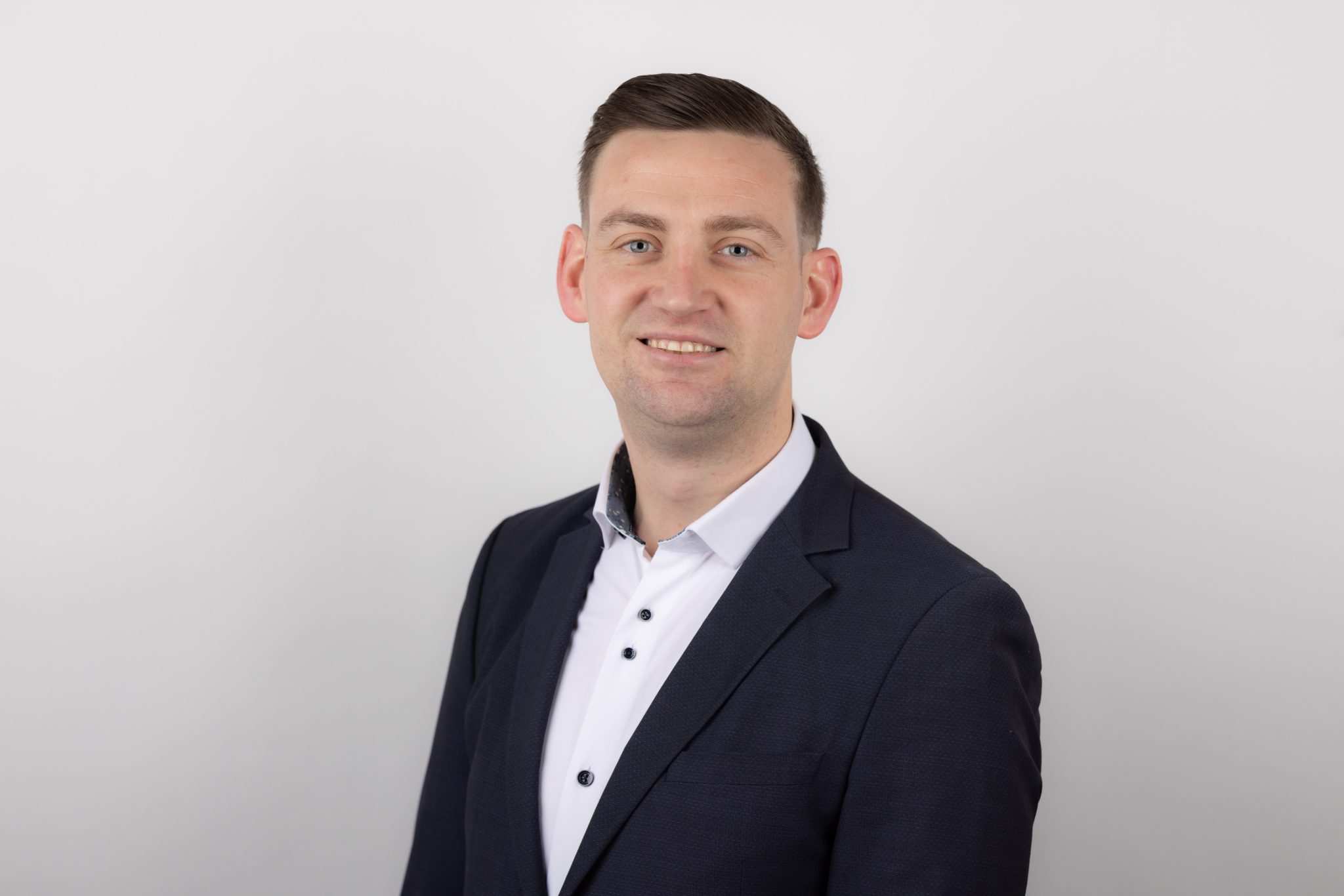 Brian Dunne in black blazer and white shirt smiling to camera.