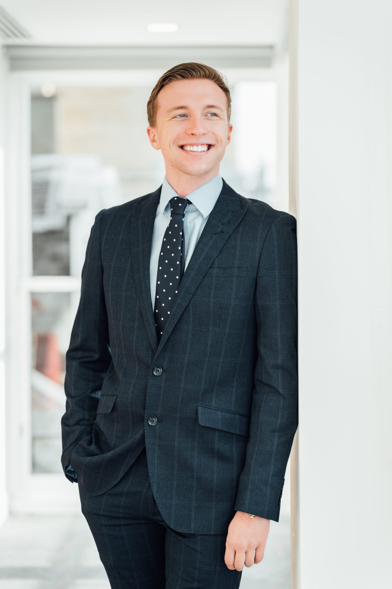 An image of Fraser Mackay wearing a suit and tie. He is standing in the office with his hand in his pocket.