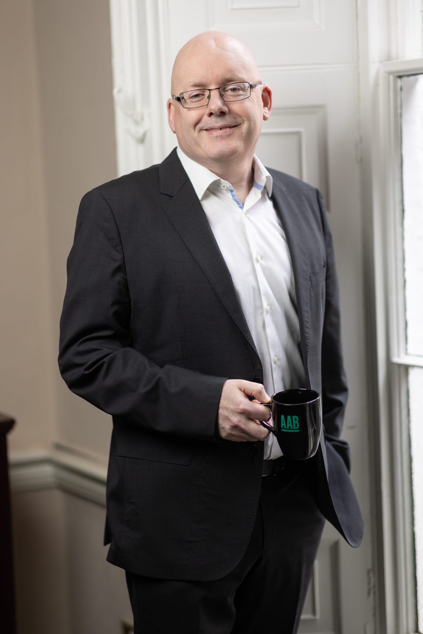 An image of Garret Wynne wearing a black suit jacket and white shirt. He is smiling at the camera.