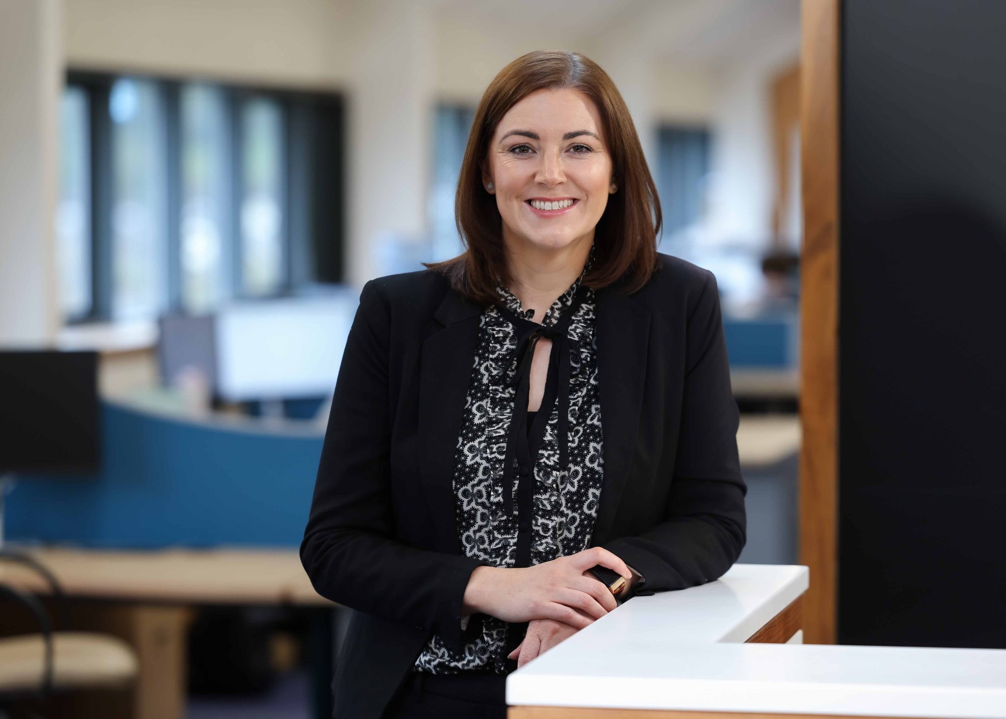 An image of Tanya standing in the Newry office and wearing a black blazer.