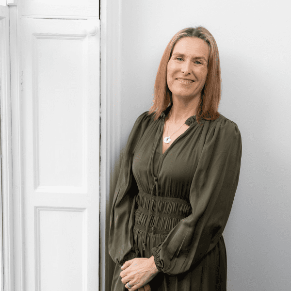 An image of Sylvia Stanbridge wearing a green dress and smiling at the camera.
