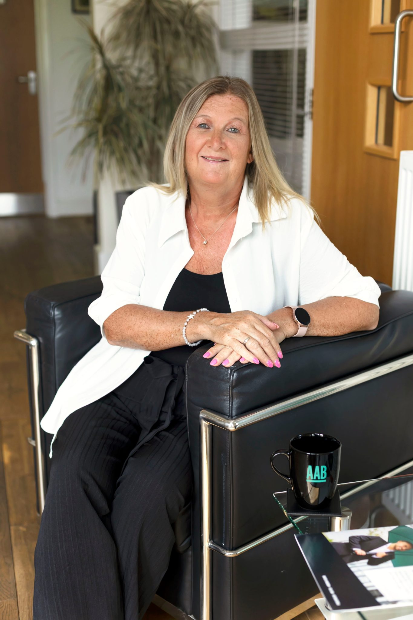 An image of Karen Lane sitting on a chair and smiling at the camera.