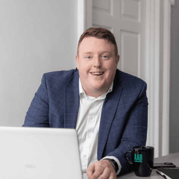 An image of Paul Giblin sitting at a desk on his laptop and smiling at the camera.