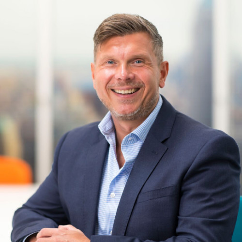 An image of Craig Blackmore wearing a navy suit and blue shirt. He is smiling at the camera.