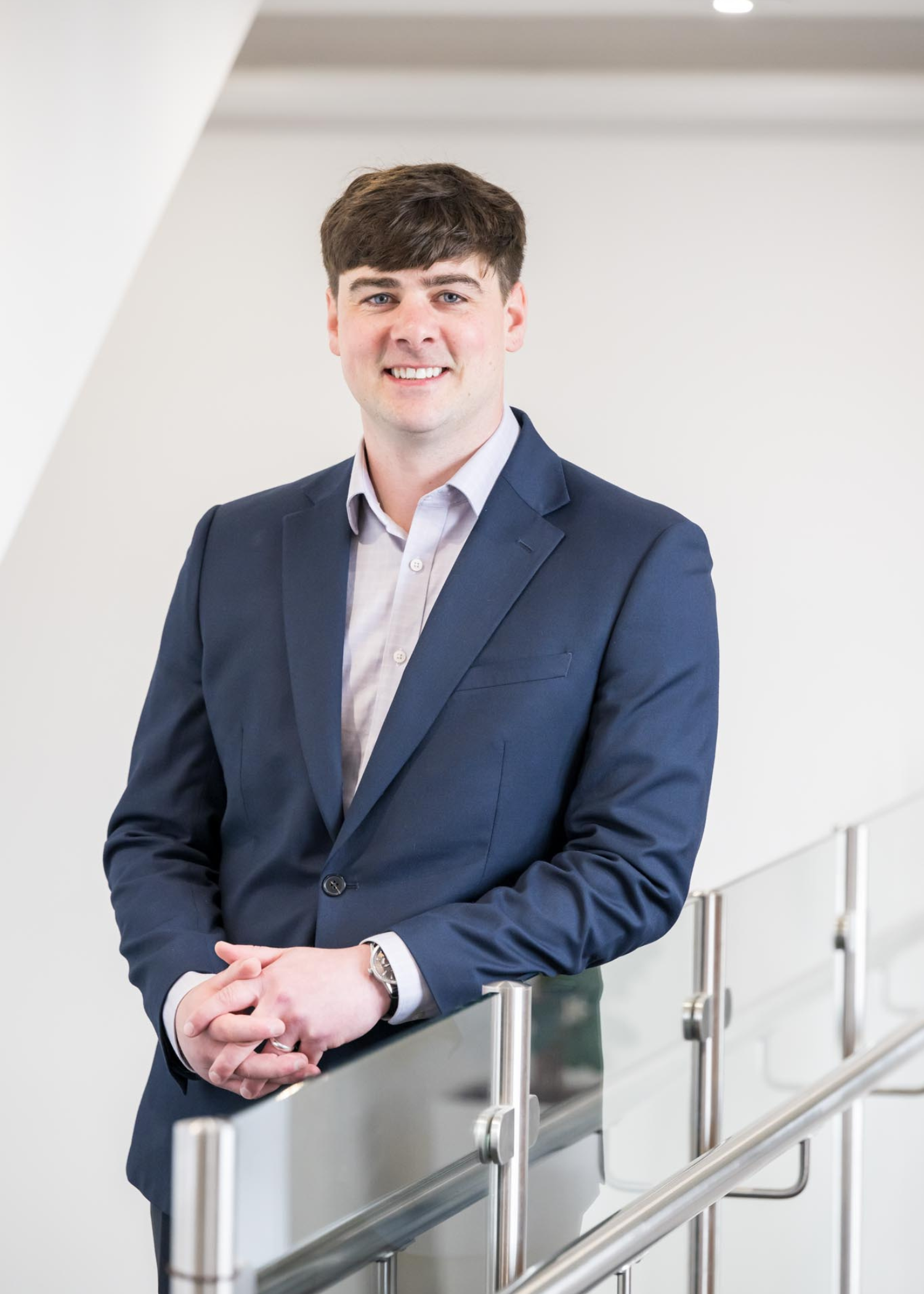 Craig Blakeman, Senior Accountant at AAB leaning against a clear glass banister in an office setting