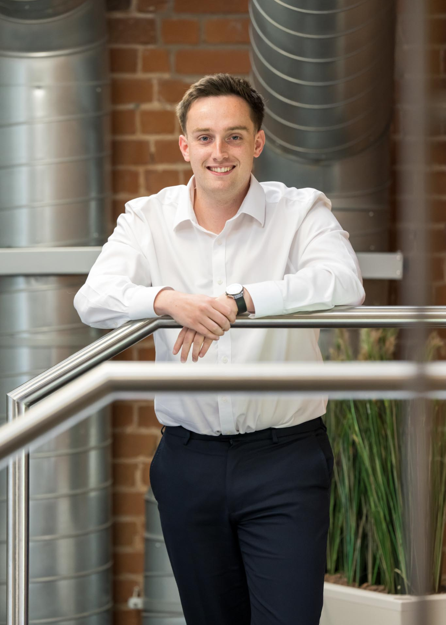 Domininc Dineen Corporate Director at AAB leaning against a clear glass banister in an office setting