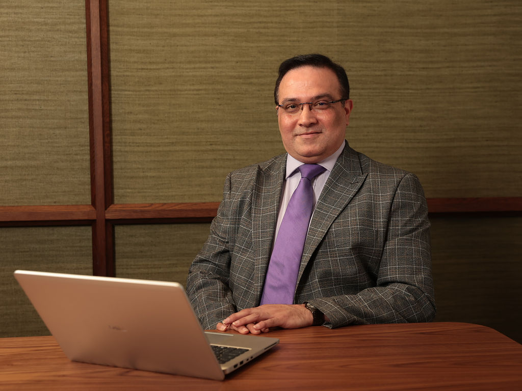An image of Burzine Karai sitting at a desk with his laptop.