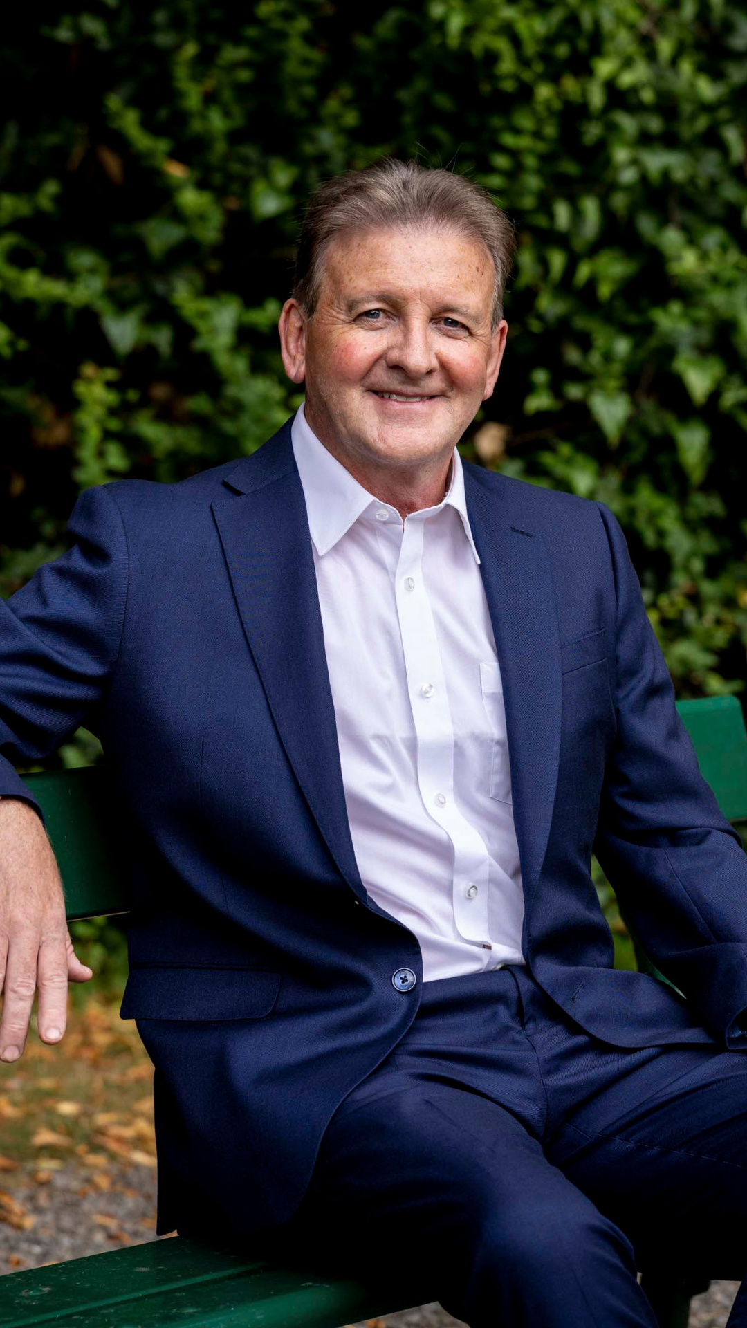 Cormac Mohan - Partner, Dublin AAB. Sat on a bench outside with foliage in the background
